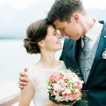 Matrimoni e feste Sposa e sposo si abbracciano con un bouquet di rose pastello vicino all'acqua
